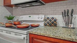 Une cuisine équipée d’une cuisinière, de casseroles, d’un four à micro-ondes et d’un porte-couteaux.