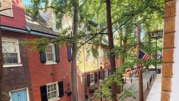 Een smalle straat met bakstenen gebouwen, een blauwe deur en een Amerikaanse vlag.