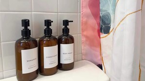 Drie flessen douche- en shampoobad staan op een badkamermeubel.