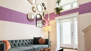A living room with a dark green sofa, a coffee table, and a patterned rug. - Pride Weekend | Balcony | Renovated Church Loft (Philadelphia)
