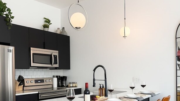 A modern kitchen with a central island, stainless steel appliances, and bar stools.