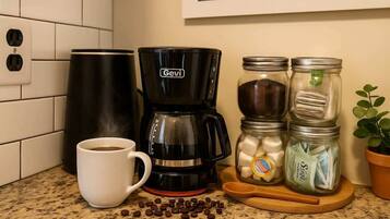 Une cuisine équipée d’une machine à café, d’une tasse et de pots contenant des grains de café.