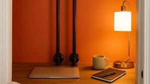 Une pièce avec un bureau, un ordinateur portable, un téléphone intelligent, une tasse de café et une lampe.