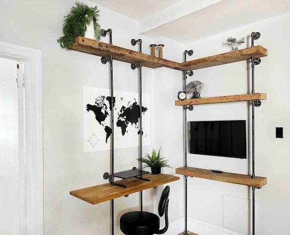 Une pièce comprenant un bureau, une carte du monde, une horloge et une plante.