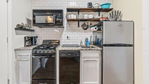 A compact kitchen with white cabinetry, a built-in microwave, a gas stove, a dishwasher, and a refrigerator. - Historic | Parking | Walk Score 98 | Cozy (Philadelphia)