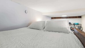 A bedroom with a bed, pillows, a small kitchenette with a sink and a blue bowl. - Historic | Parking | Walk Score 98 | Cozy (Philadelphia)