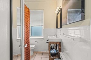 A bathroom with a toilet, sink, mirror, and window with blinds. - Historic | Parking | Walk Score 98 | Cozy (Philadelphia)