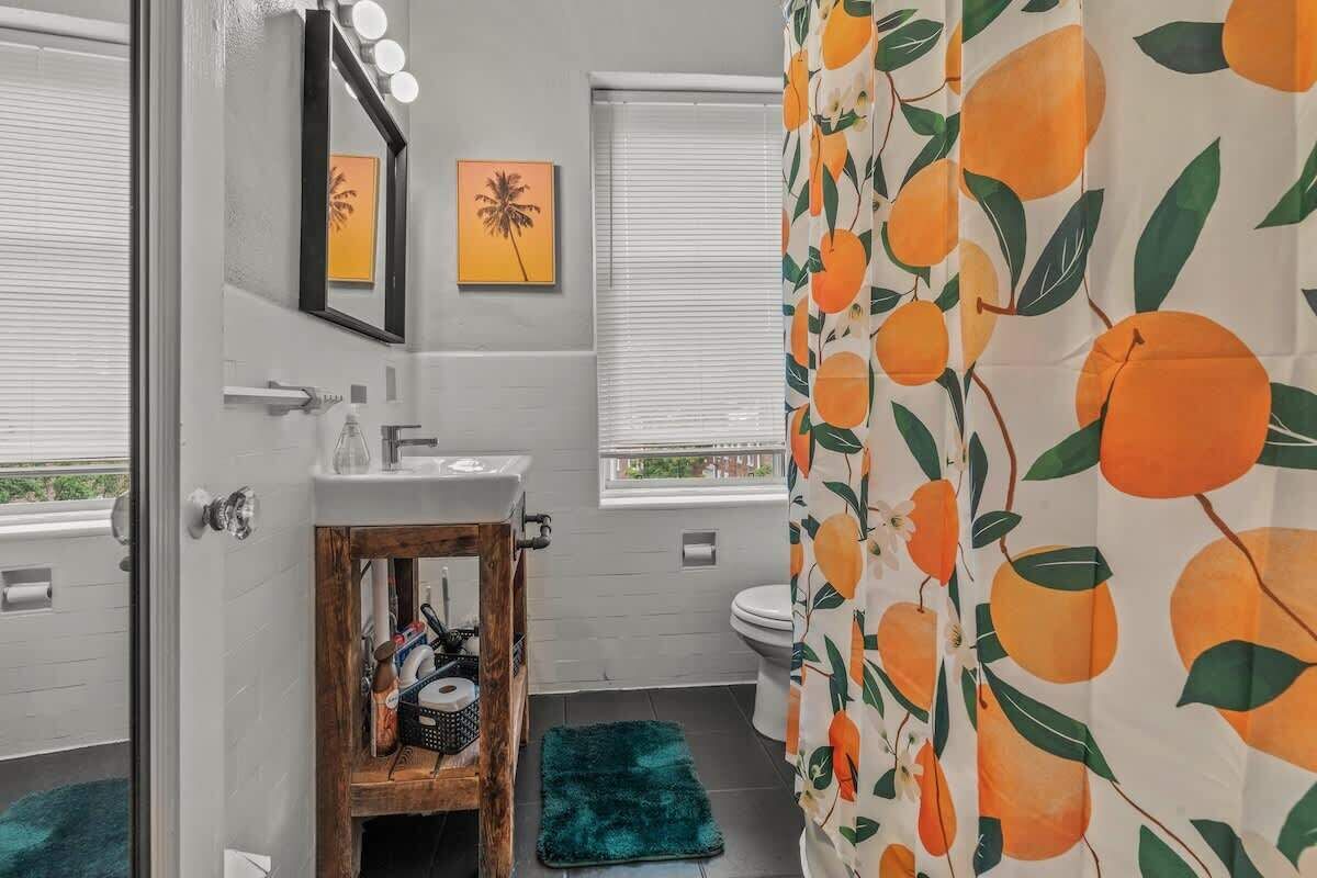Une salle de bain avec un miroir, un lavabo, des toilettes et une fenêtre avec des stores.
