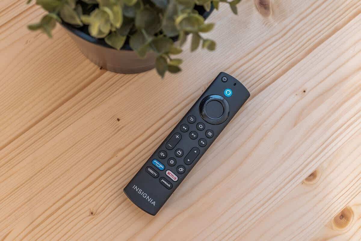 A black remote control with the brand name 'INSIGNIA' on a wooden surface.