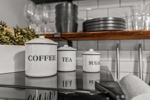 Un plan de travail de cuisine avec des bocaux de rangement étiquetés pour le café, le thé, le sucre et les citrons.