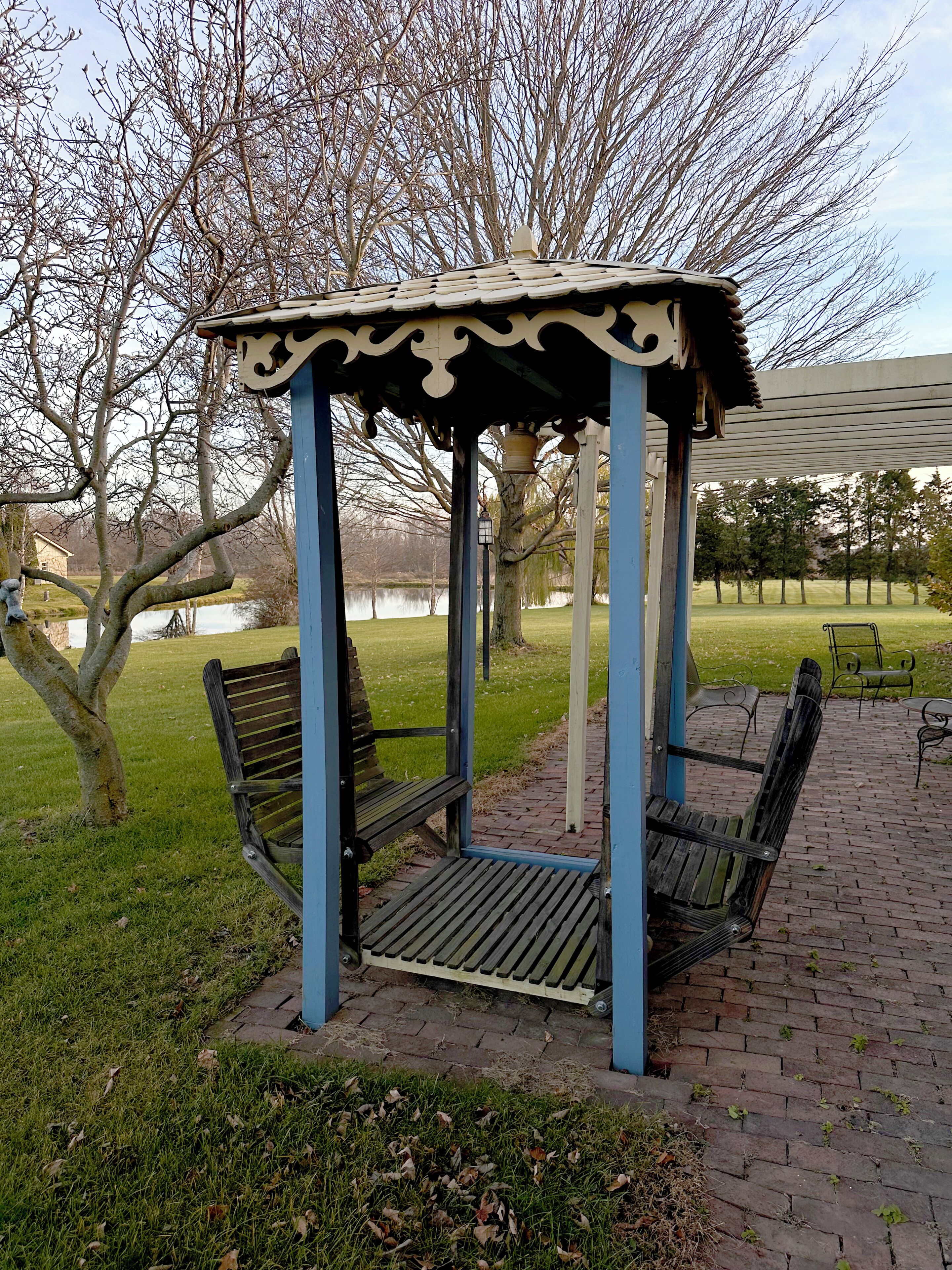 A gazebo with benches, a brick pathway, and a grassy area with trees.