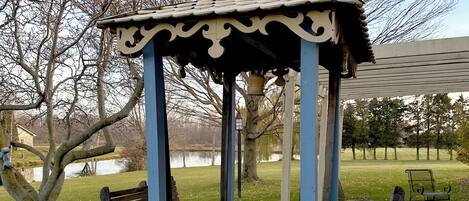 A gazebo with benches, a brick pathway, and a grassy area with trees.