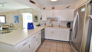 A kitchen with white cabinets, a stainless steel refrigerator, and a tiled floor. - 20% off week of July 25-Aug. 1.  3BR OF condo. Ocean Drive. Pool. (North Myrtle Beach)