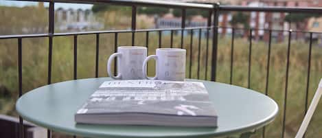 A balcony with a table holding two Italianway mugs and a magazine.