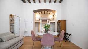 Un interior moderno con una mesa de comedor redonda, dos sillas rosas, un sofá y un mueble de madera.