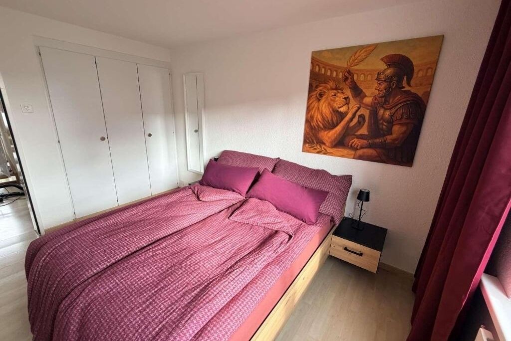 Ein Schlafzimmer mit Bett, Nachttisch, Schublade, einem Gemälde und einem Kleiderschrank.