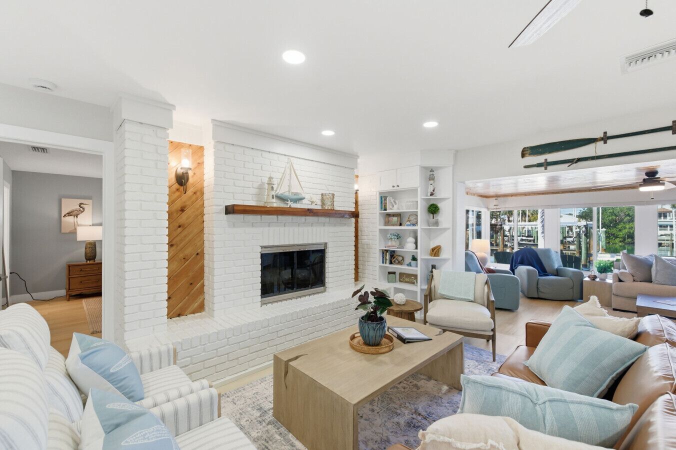 A modern living room with a fireplace, white brick walls, and a view of the outdoors.