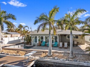 A house with a swimming pool, outdoor seating, and palm trees. - Waterfront Home with Pool in Indian Rocks Beach (Indian Rocks Beach)
