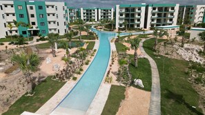 A resort with a central swimming pool, multiple-story buildings, and landscaped areas with palm trees. - Modern Comfort in Serena Village Your Punta Cana Retreat (Punta Cana)