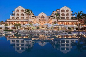 Un hotel con un patio central, piscina y el reflejo del edificio.