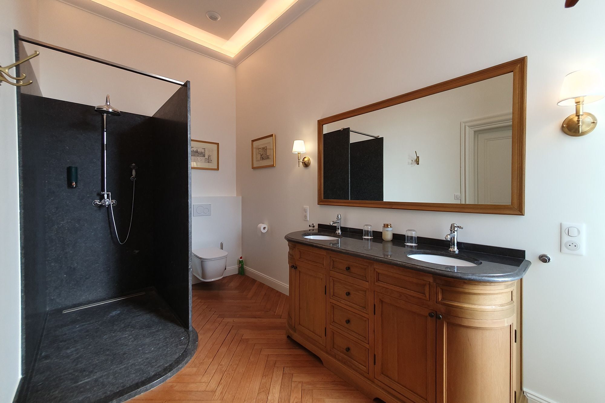 Une salle de bain équipée d’une douche, de toilettes, d’un meuble-lavabo avec un miroir et d’armoires en bois.