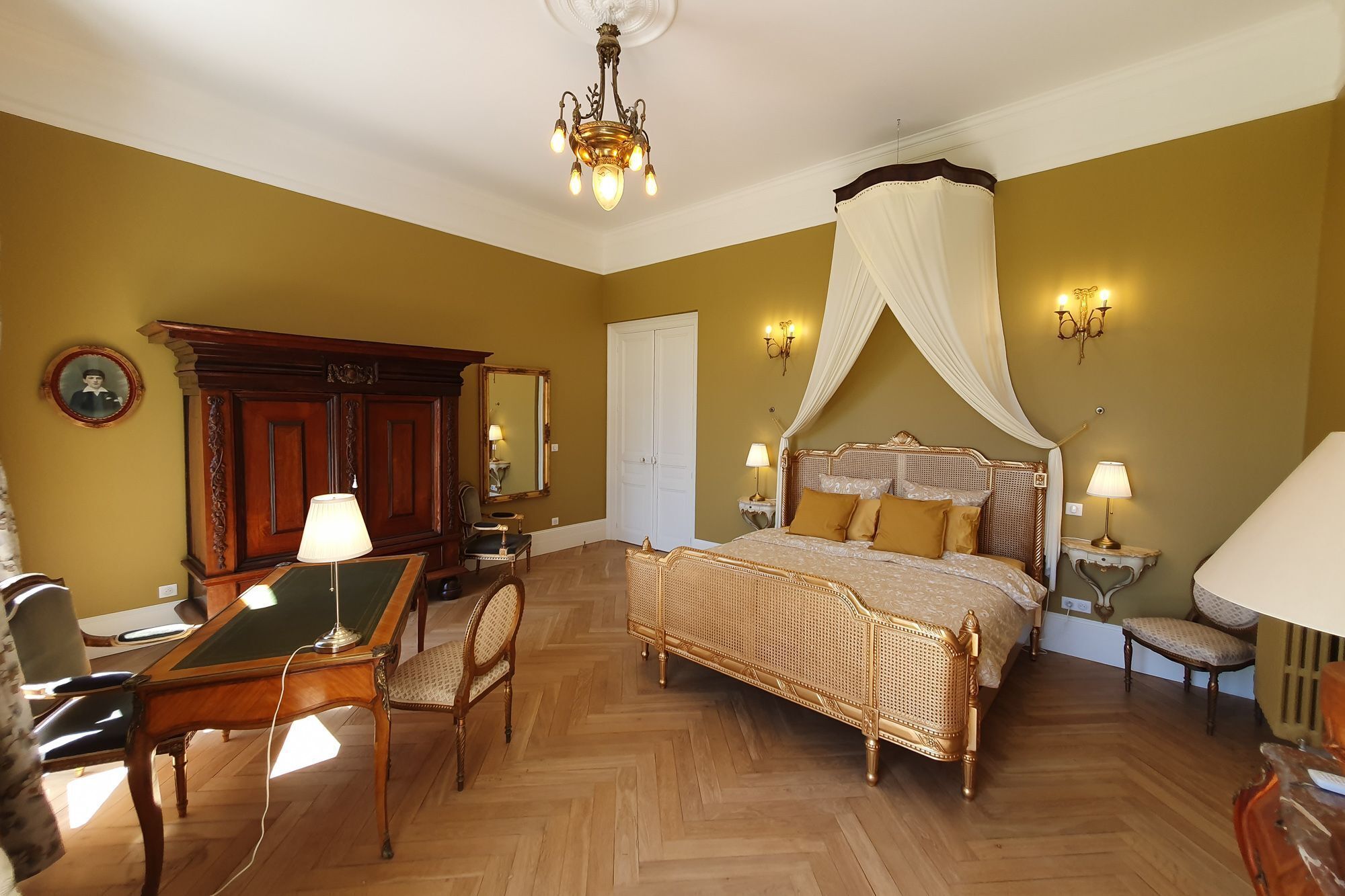 Un dormitorio con una cama con dosel, un escritorio de madera, una silla y un espejo.