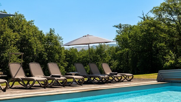 Ein Poolbereich mit Liegestühlen und einem Sonnenschirm.