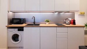 A compact kitchen with a washing machine, microwave, sink, and a small potted plant. - notaMI - Civitali Suite - San Siro (Milan)