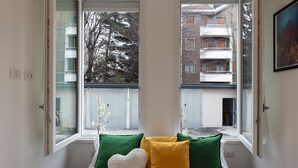 A bedroom with a bed, pillows, and a window with a view of a balcony and buildings. - notaMI - Civitali Suite - San Siro (Milan)