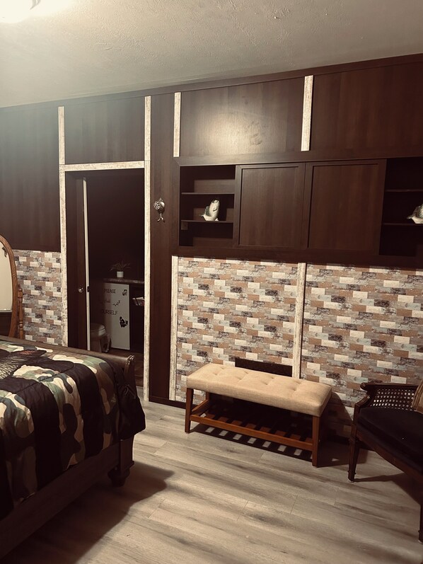 A bedroom with a bed, a bench, a wardrobe, and a small shelf.