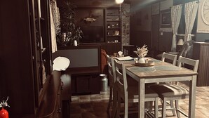 A kitchen with a dining table, chairs, cabinets, a ceiling fan, and a clock on the wall.