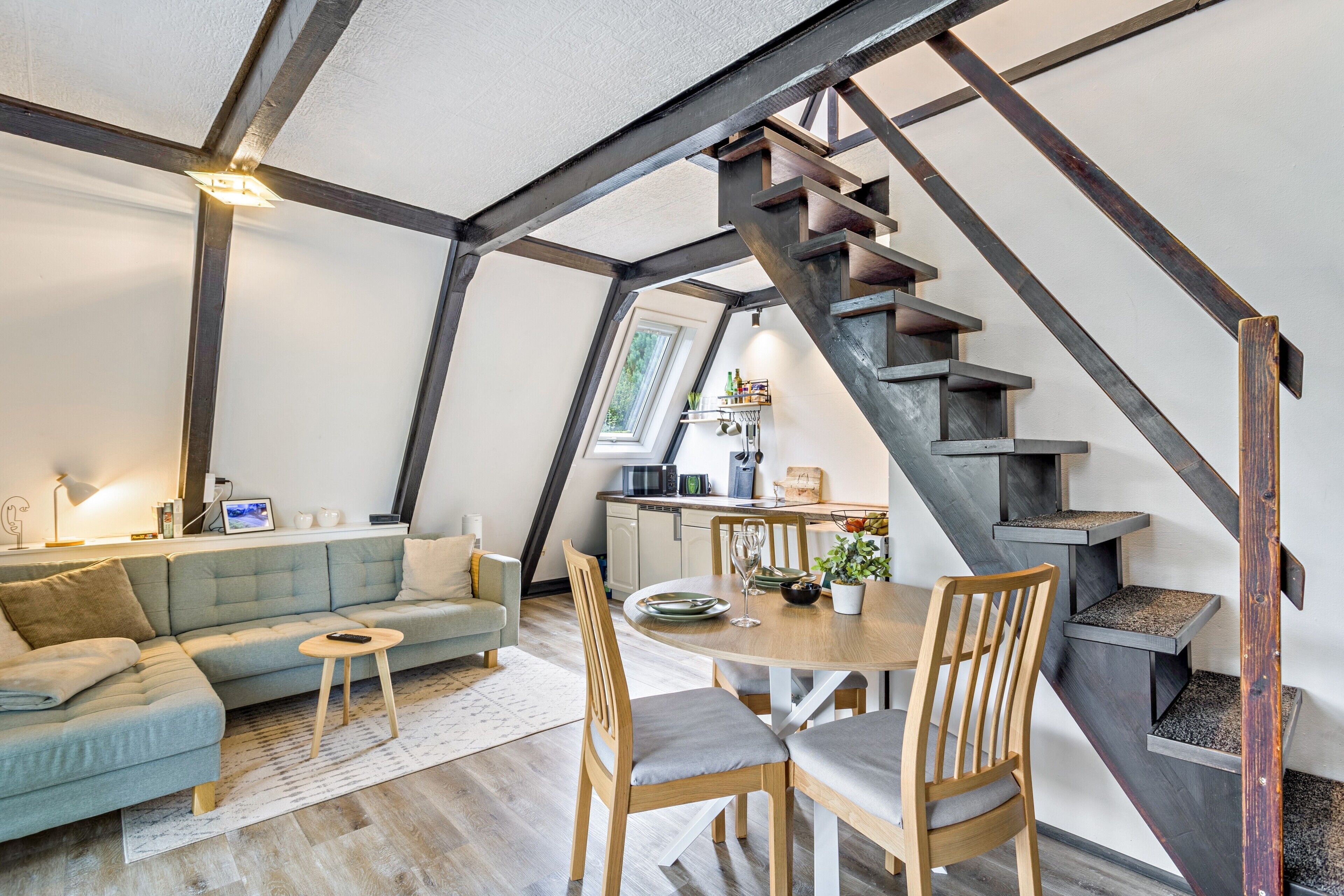 A loft-style living space with a dining area, a staircase, and a kitchen.