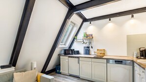 Et køkken med hvide skabe, en mikroovn og en kaffemaskine.