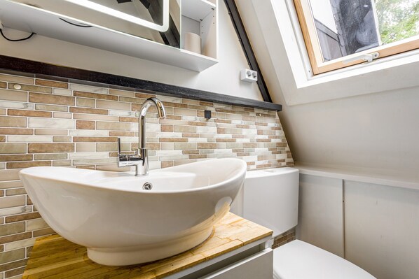 A bathroom with a white sink, a wooden countertop, and a tiled backsplash.
