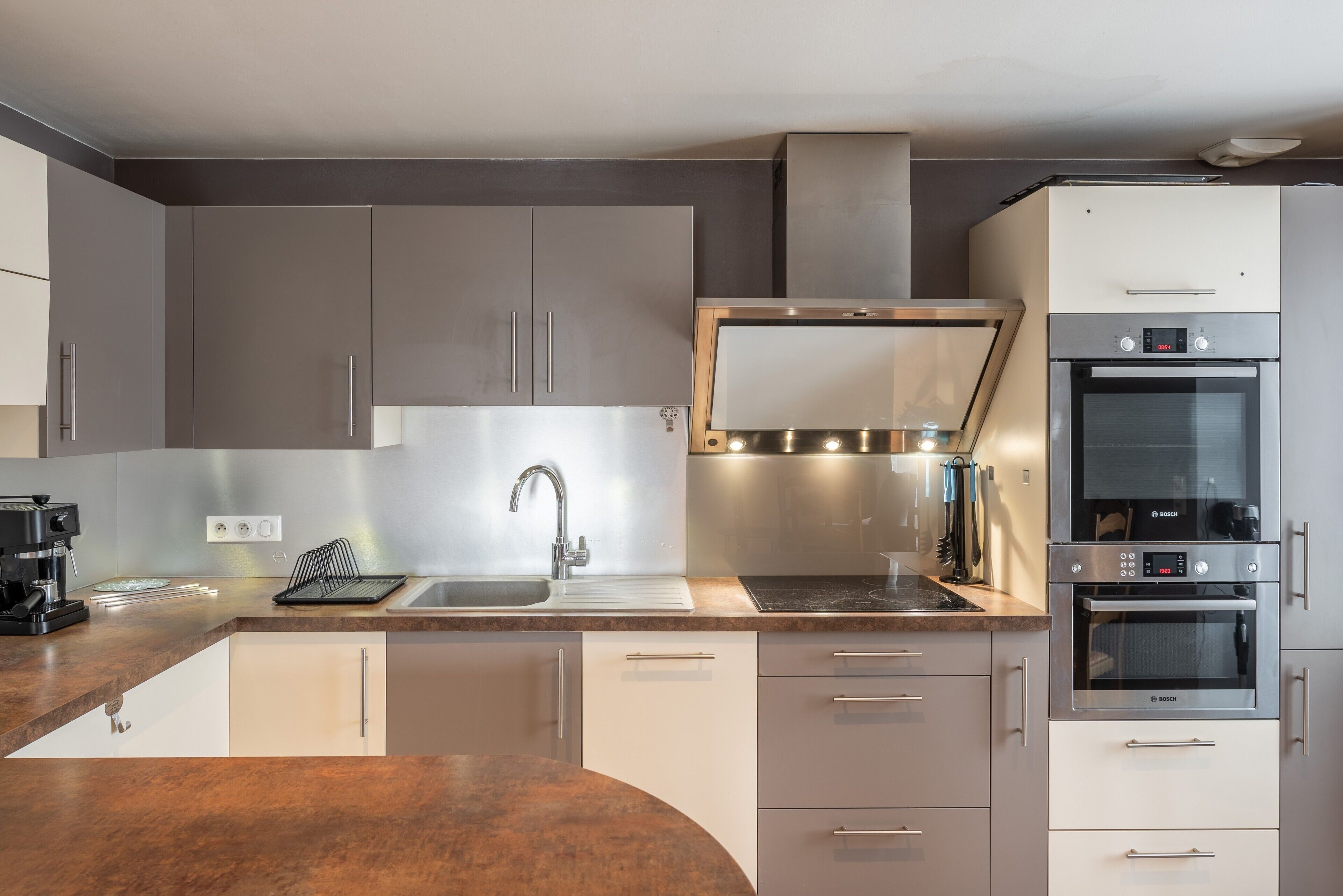 Una cocina moderna con horno empotrado, electrodomésticos de acero inoxidable y un lavamanos.