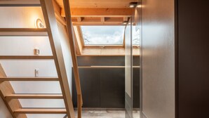 Ein enger Flur mit einer Holzleiter, einem Oberlicht und einem modernen Innenarchitekturstil.