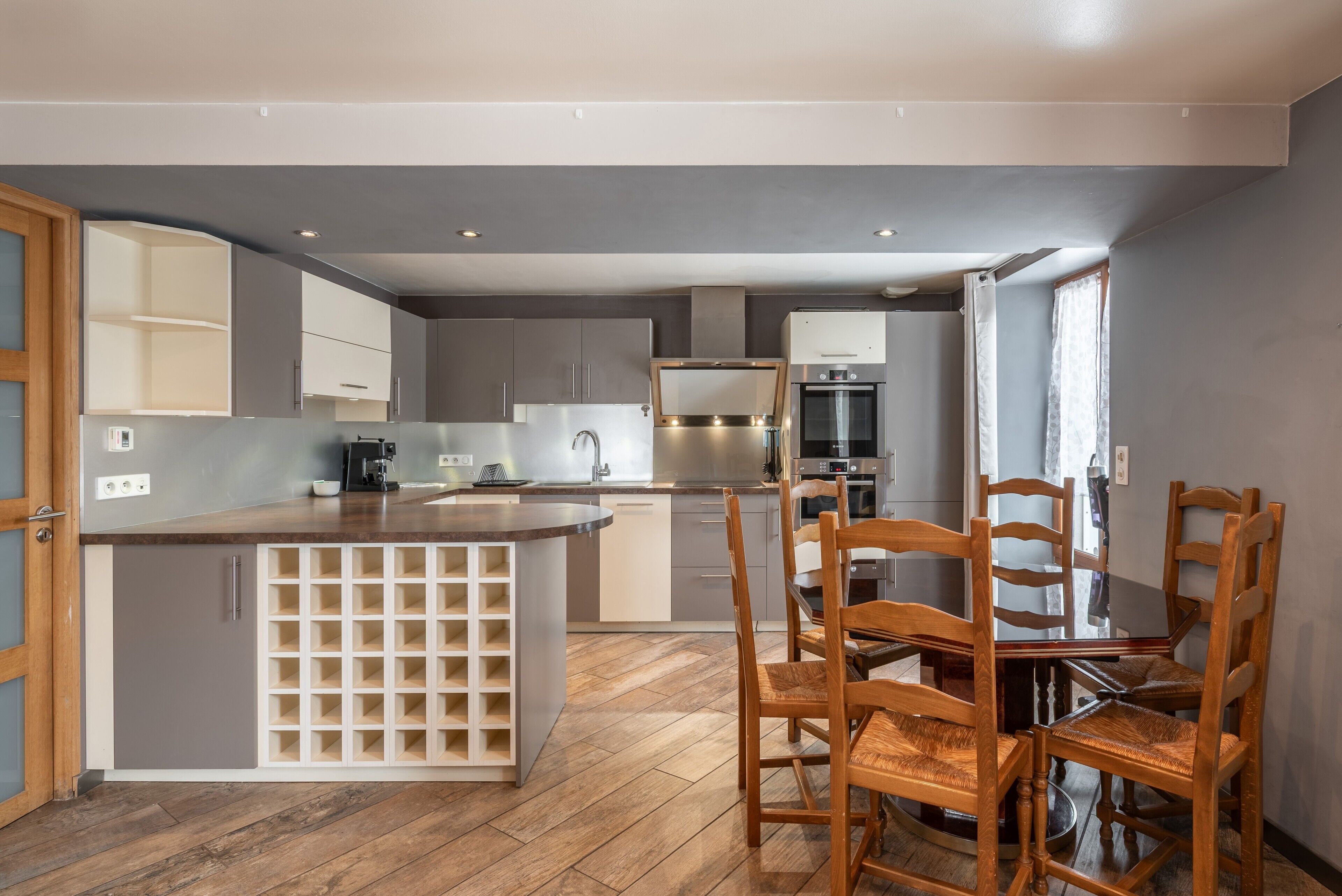 Una cucina moderna con isola centrale, sedie in legno e mobili a incasso.
