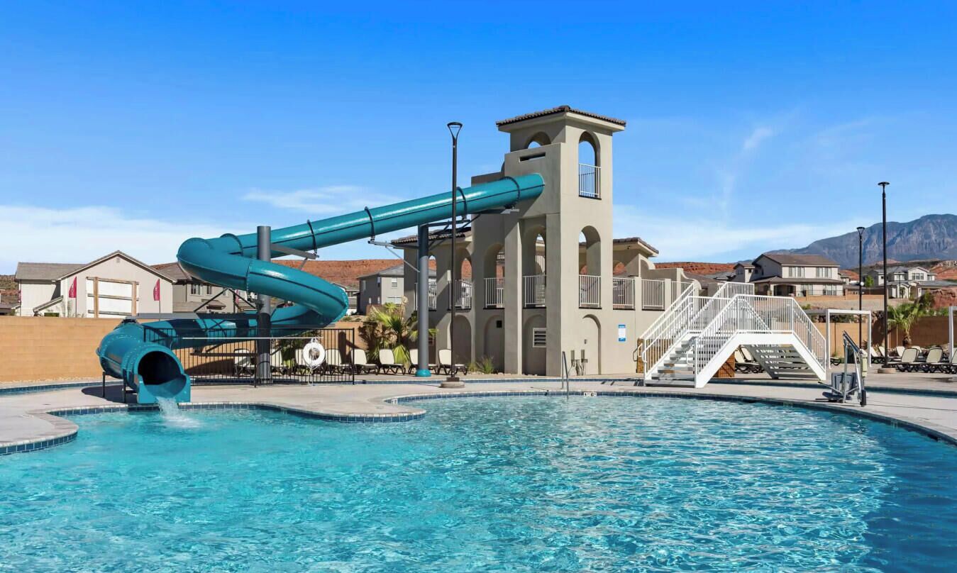 A swimming pool with a blue slide, a tower structure, and a staircase leading to a balcony.