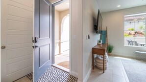 A hallway with a door leading to a room, a small table with a plant, and a window with a view of the outdoors. - Spacious Getaway w/Heated Pool (Washington)
