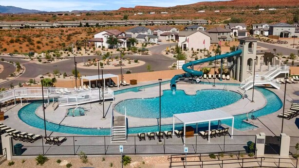 A swimming pool with a water slide, lounge chairs, and a view of a desert landscape. - Spacious Getaway w/Heated Pool (Washington)