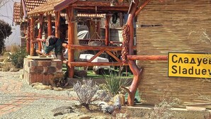 Un bâtiment rustique en bois, doté d’un toit en tuiles, d’une enseigne et d’une personne travaillant à une table en bois.