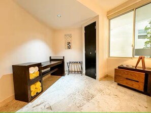 Ein Zimmer mit Marmorboden, einer dunklen Holzbank, einem kleinen Tisch mit Lampe und einem großen Fenster.