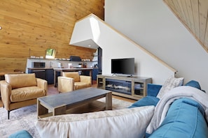 Un espace de vie moderne comprenant une chambre en mezzanine, un coin cuisine et un téléviseur.