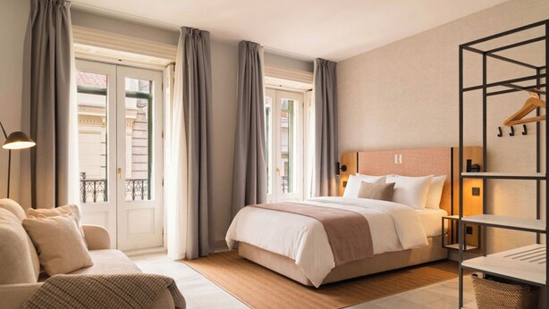 Een hotelkamer met een bed, een slaapbank, een bureau en uitzicht op het omliggende landschap.