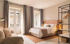 A hotel room with a bed, a sofa, a desk, and a view of the outside. - Limehome Madrid Sol (Madrid)