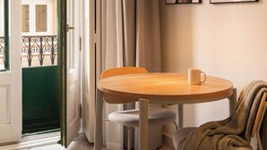 Een kamer met een ronde houten tafel, een stoel, een kleedje en een raam met gordijnen.