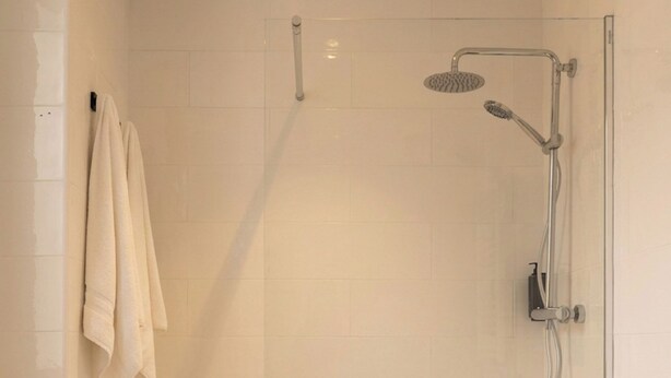 A glass-enclosed shower with a handheld showerhead and a wall-mounted faucet. - Limehome Madrid Sol (Madrid)