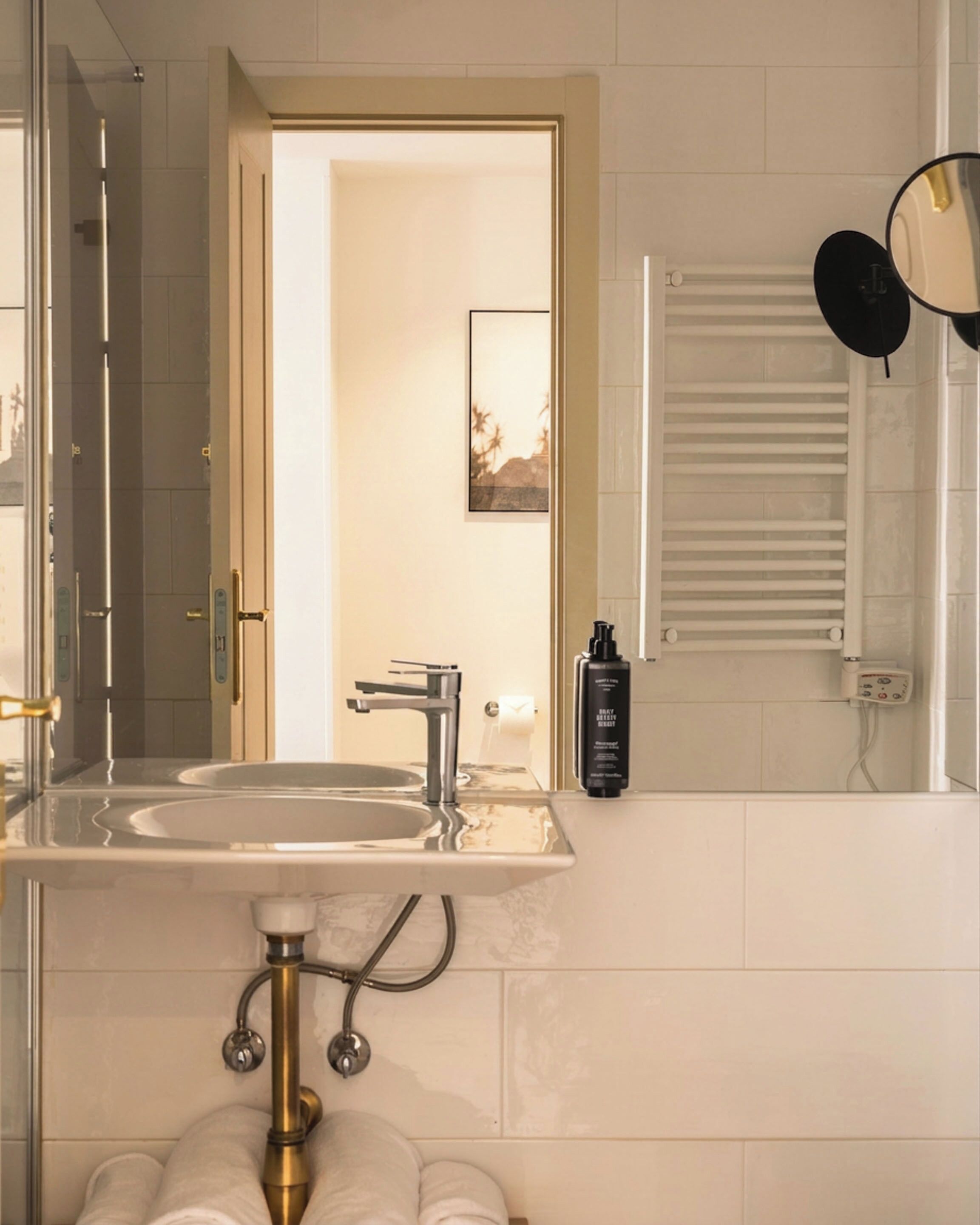 A bathroom with a sink, mirror, towel rack, and a door leading to another room.