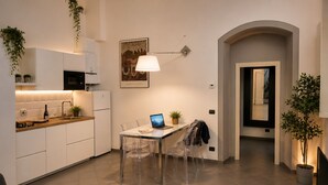Eine moderne Küche mit weißen Schränken, ein Essbereich mit klaren Stühlen und ein Laptop auf dem Tisch.