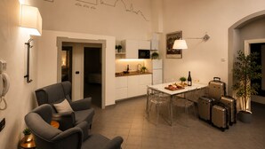 Ein modernes Wohnzimmer mit Sofa, einem Esstisch mit Stühlen, einer Küchenzeile und einer Treppe, die in ein weiteres Stockwerk führt.